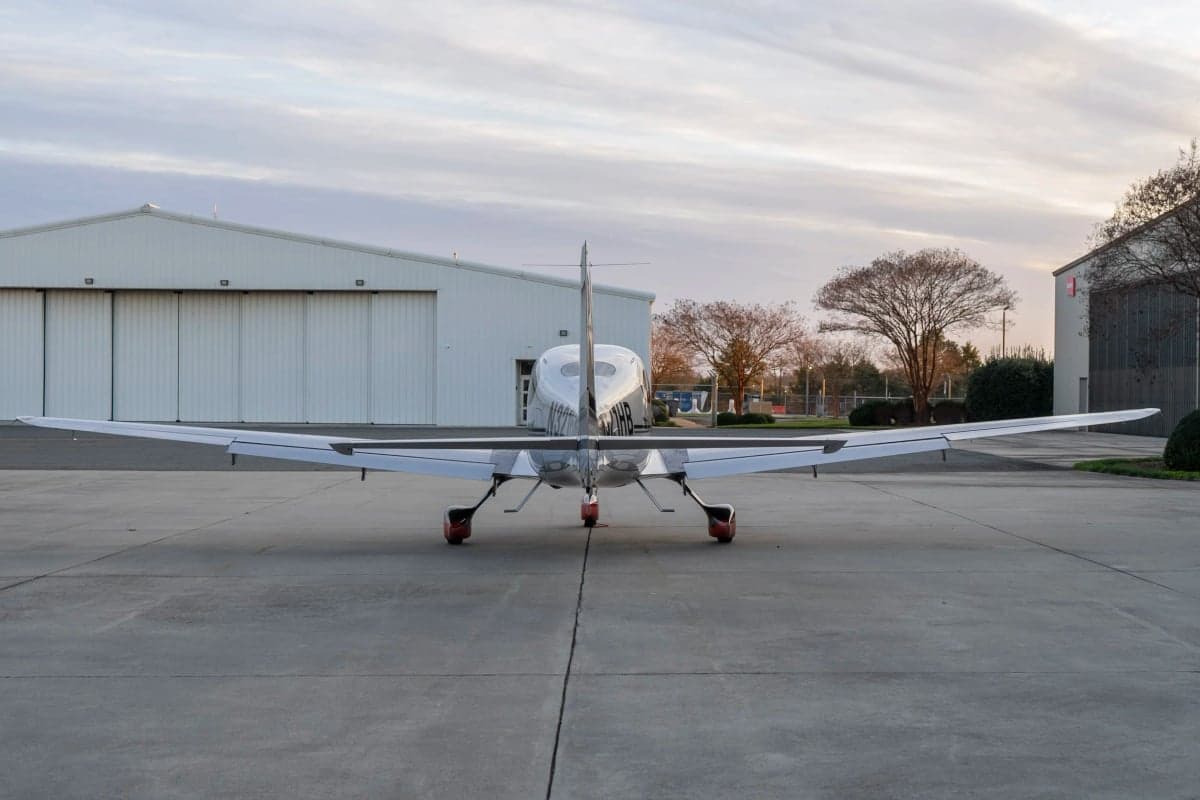 Rear view of a Cirrus SR22T aircraft with a silver paint scheme parked on the tarmac.