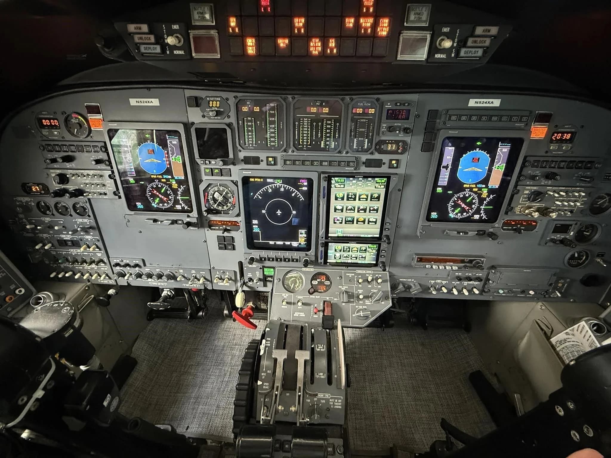 A wide view of the cockpit of the N524XA business jet, featuring the instrument panel, throttle quadrant, and pilot seats.