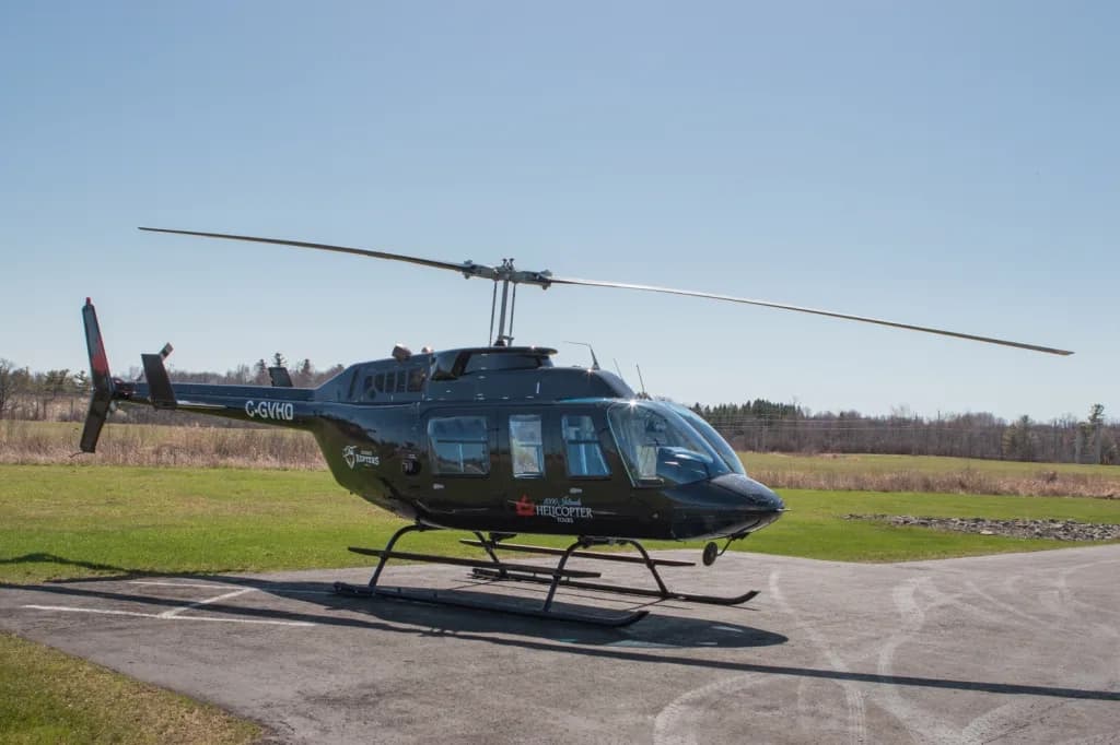 A black Bell 206 helicopter with registration C-GVHD is parked on a tarmac, viewed from the front-right.