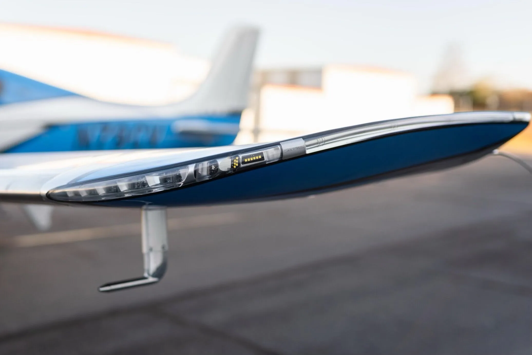 A close-up view of the wingtip light and navigation lights on the blue and silver Cirrus SR22T GTS aircraft.