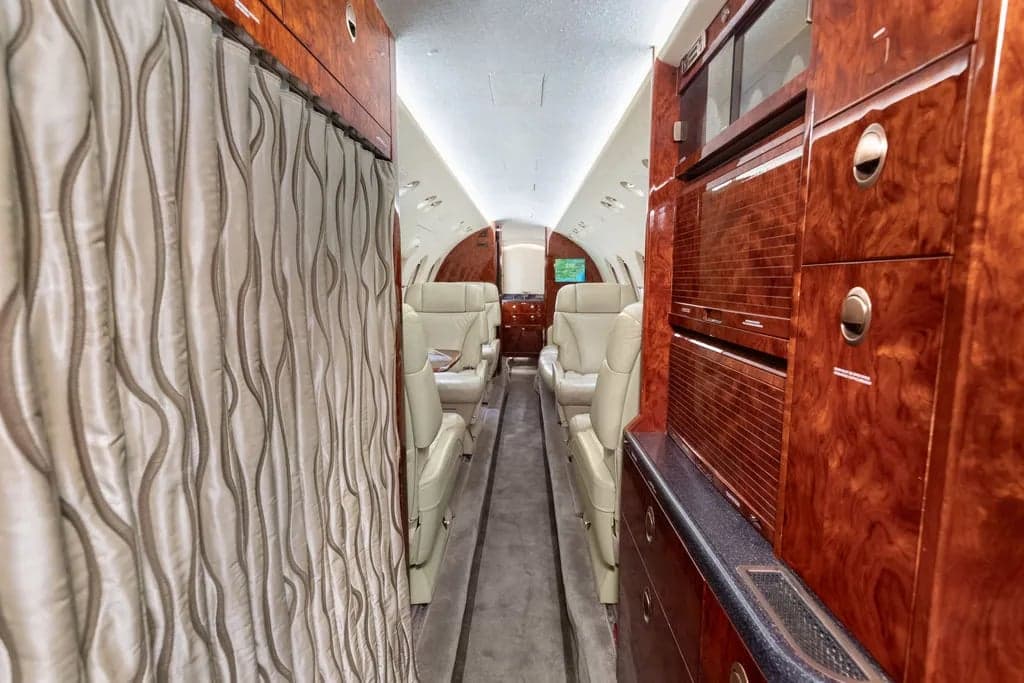 Interior view of the aircraft cabin showing the aisle, seats, and cabinetry.