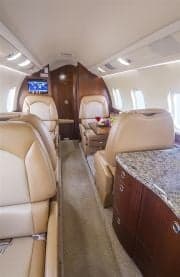 View of the Learjet cabin interior with leather seats and wood trim.