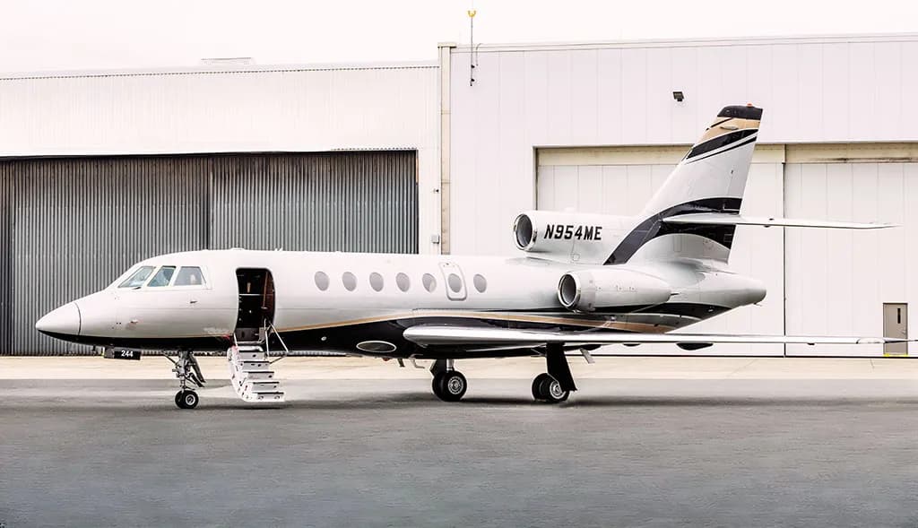 A Dassault Falcon 900EX business jet, registration N954ME, parked on the tarmac with its main cabin door open.