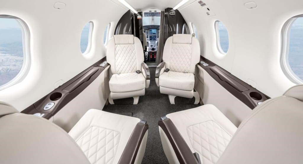 Interior view of the aircraft cabin with white leather seats.