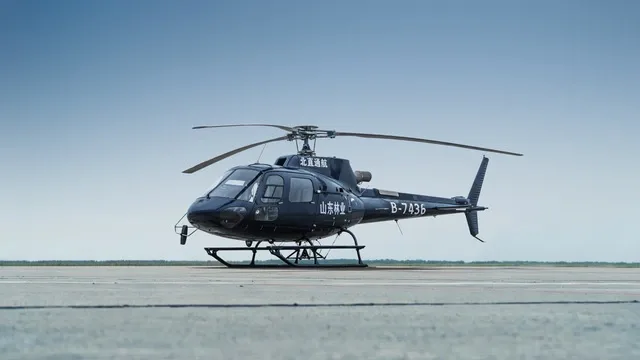 A dark blue helicopter with registration B-7436 parked on an airfield under a clear sky.