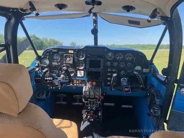 The cockpit of a light aircraft features a blue instrument panel with various gauges and a central display.