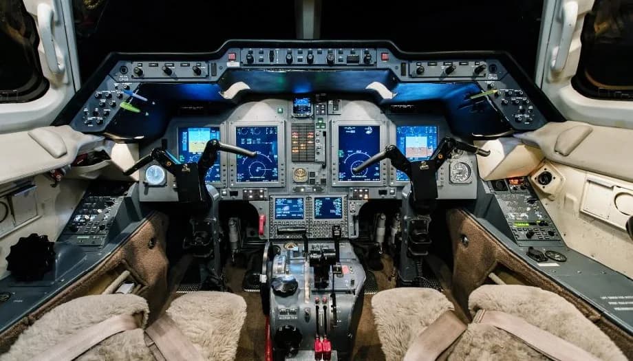 The cockpit of a Citation jet with blue instrument panel lighting.