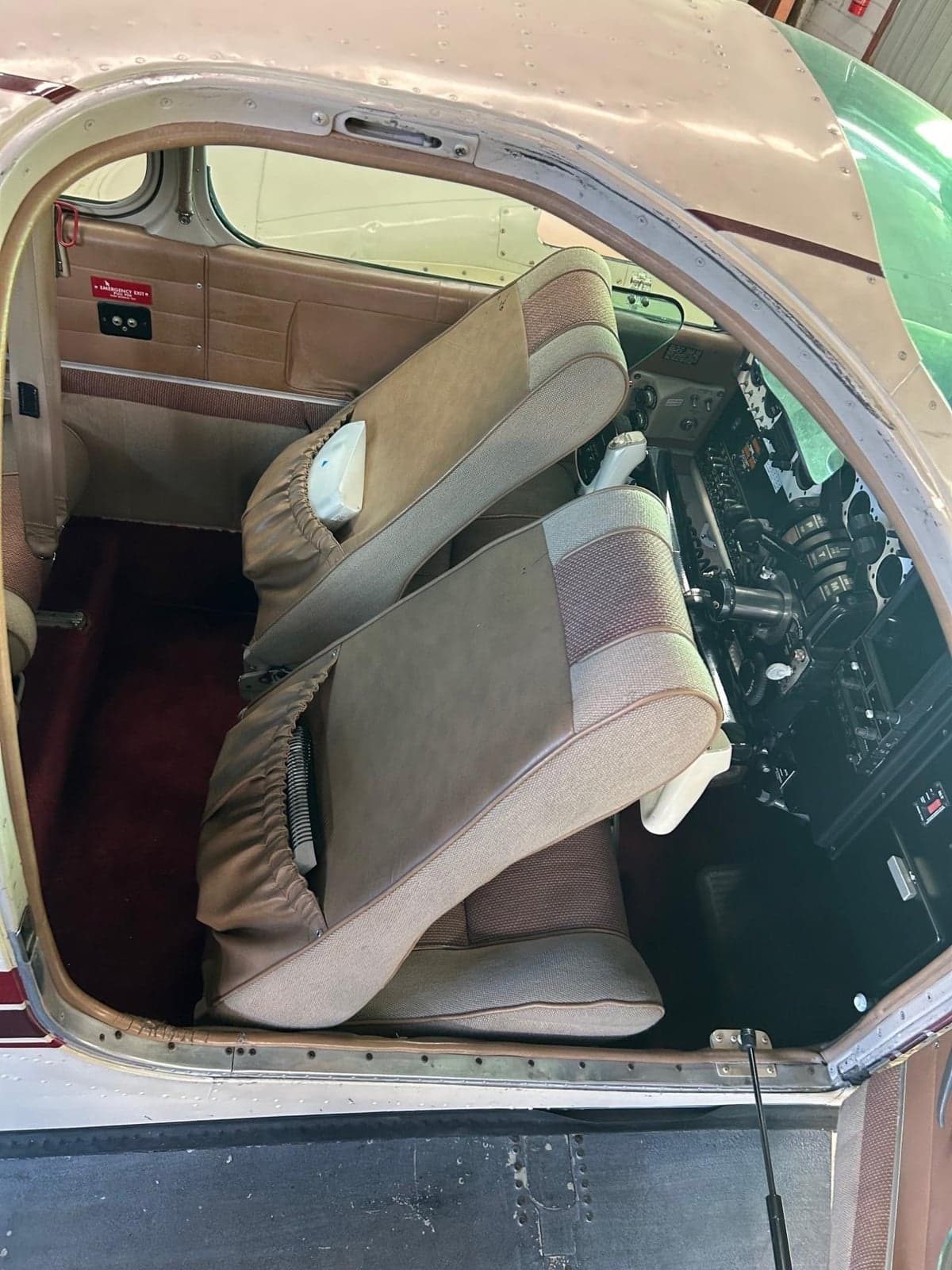 The aircraft's front seats tilted forward, revealing the instrument panel and cockpit controls.