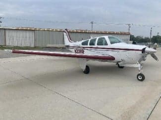 Side view of a white and red Beechcraft Bonanza with tail number N30819 on the ramp.