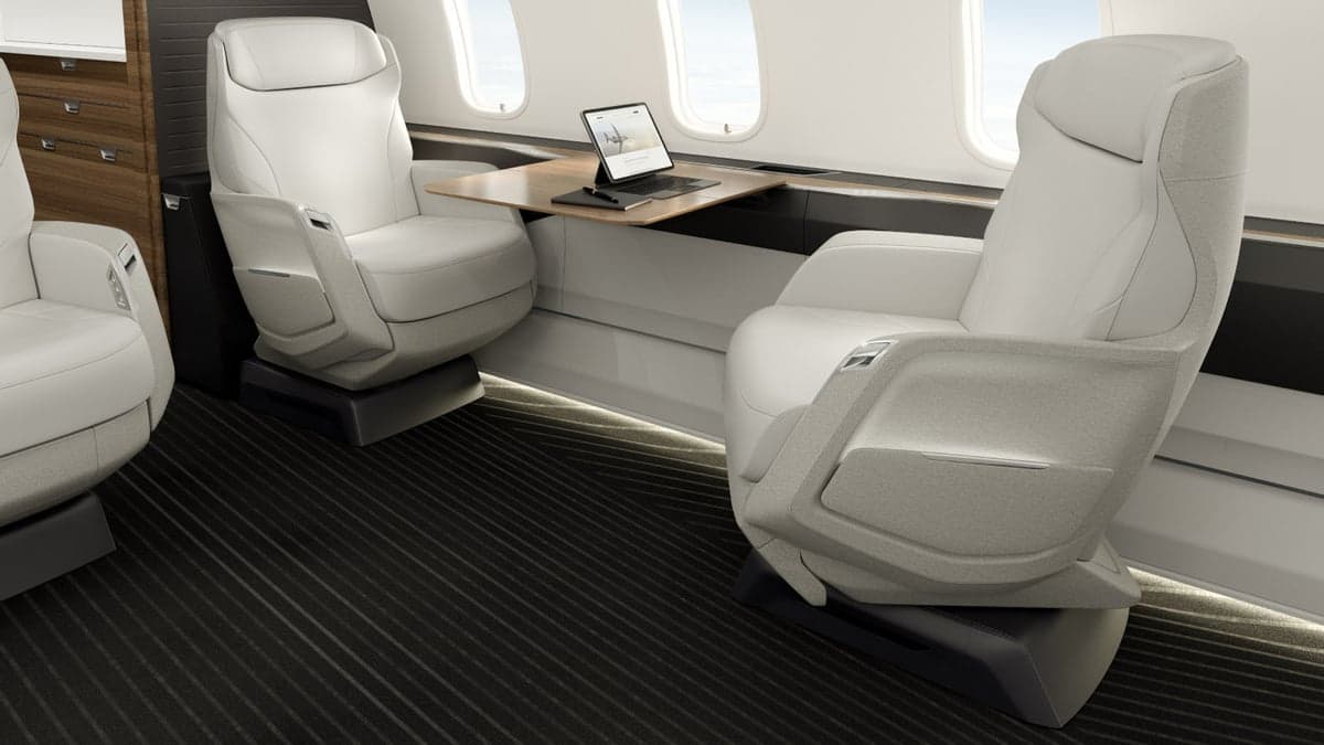 A view of the Challenger 3500 cabin with white leather seats and a table.