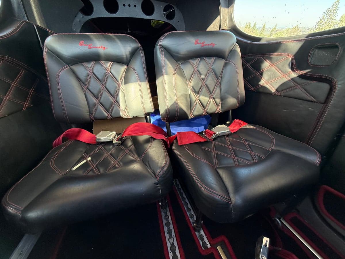 The interior of the aircraft features black leather seats with red stitching.