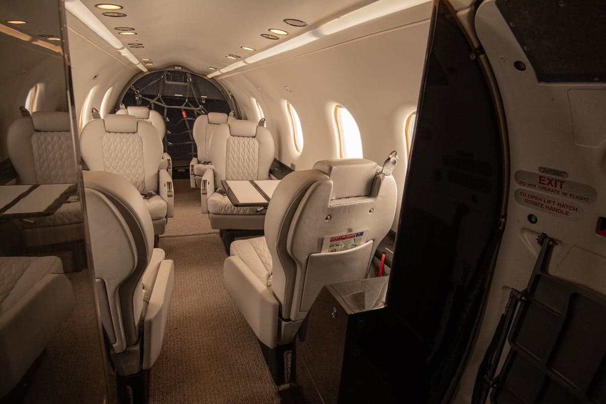 View of the aircraft cabin featuring white leather seats and a folding table.