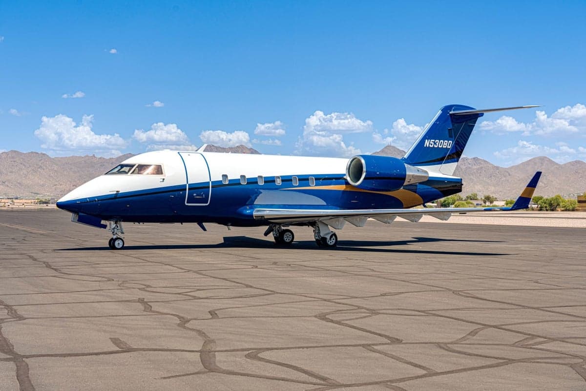 A blue and white Bombardier Challenger 300 on the tarmac.