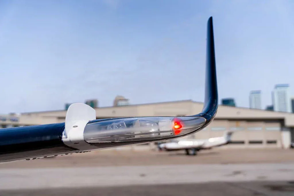 A close-up view of the wingtip of an aircraft, showing a red navigation light.
