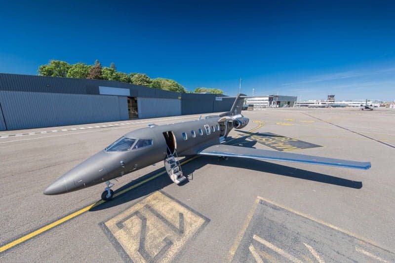 A Bombardier Challenger 350 aircraft with registration LX-VGF is parked on the tarmac at an airport.