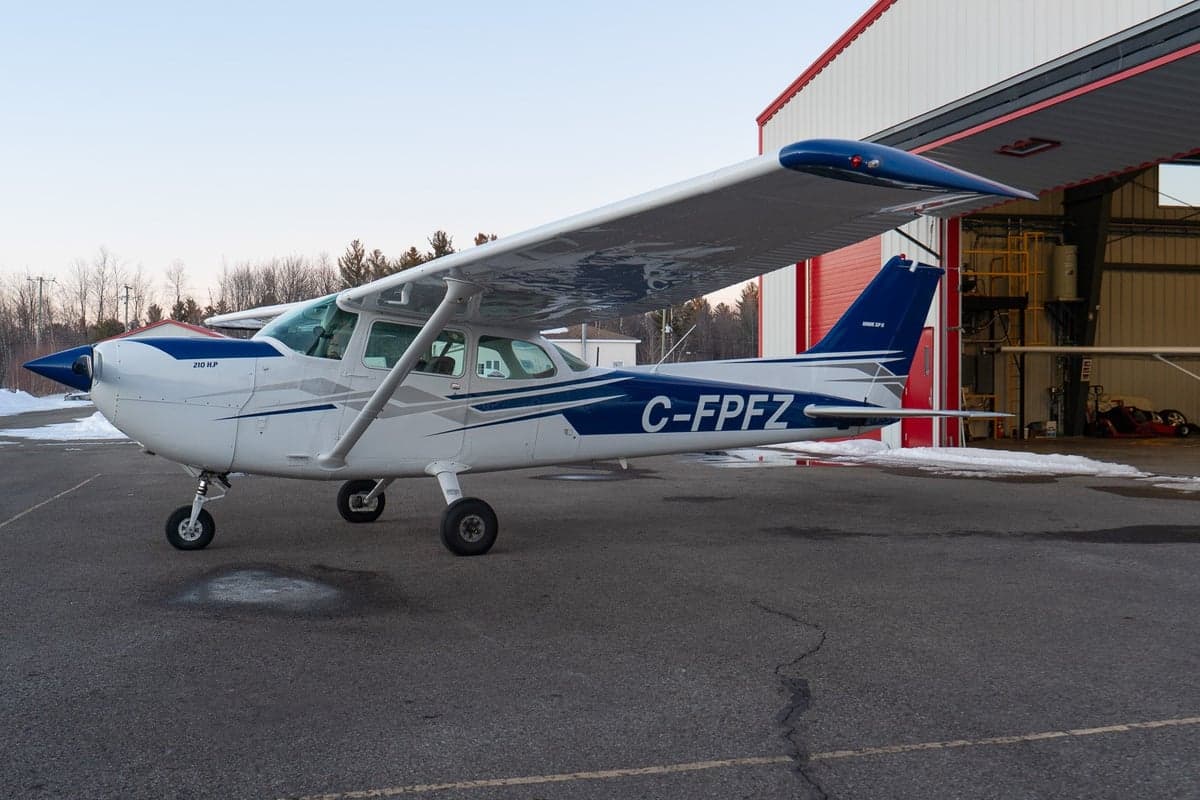Cessna 210 HP aircraft C-FPFZ parked outside a hangar.