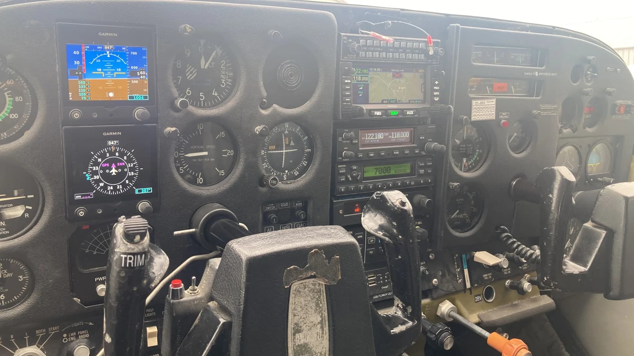 The instrument panel of a Cessna aircraft featuring analog gauges and modern Garmin avionics displays.