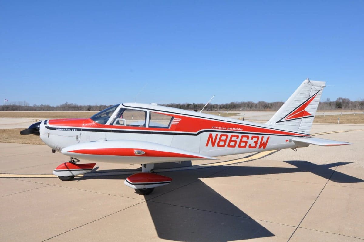 A Cherokee 180 aircraft is parked on the tarmac.