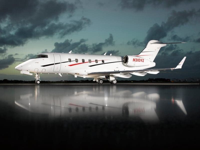 A Bombardier Challenger 350 aircraft with registration N310VZ is parked on the tarmac at dusk.