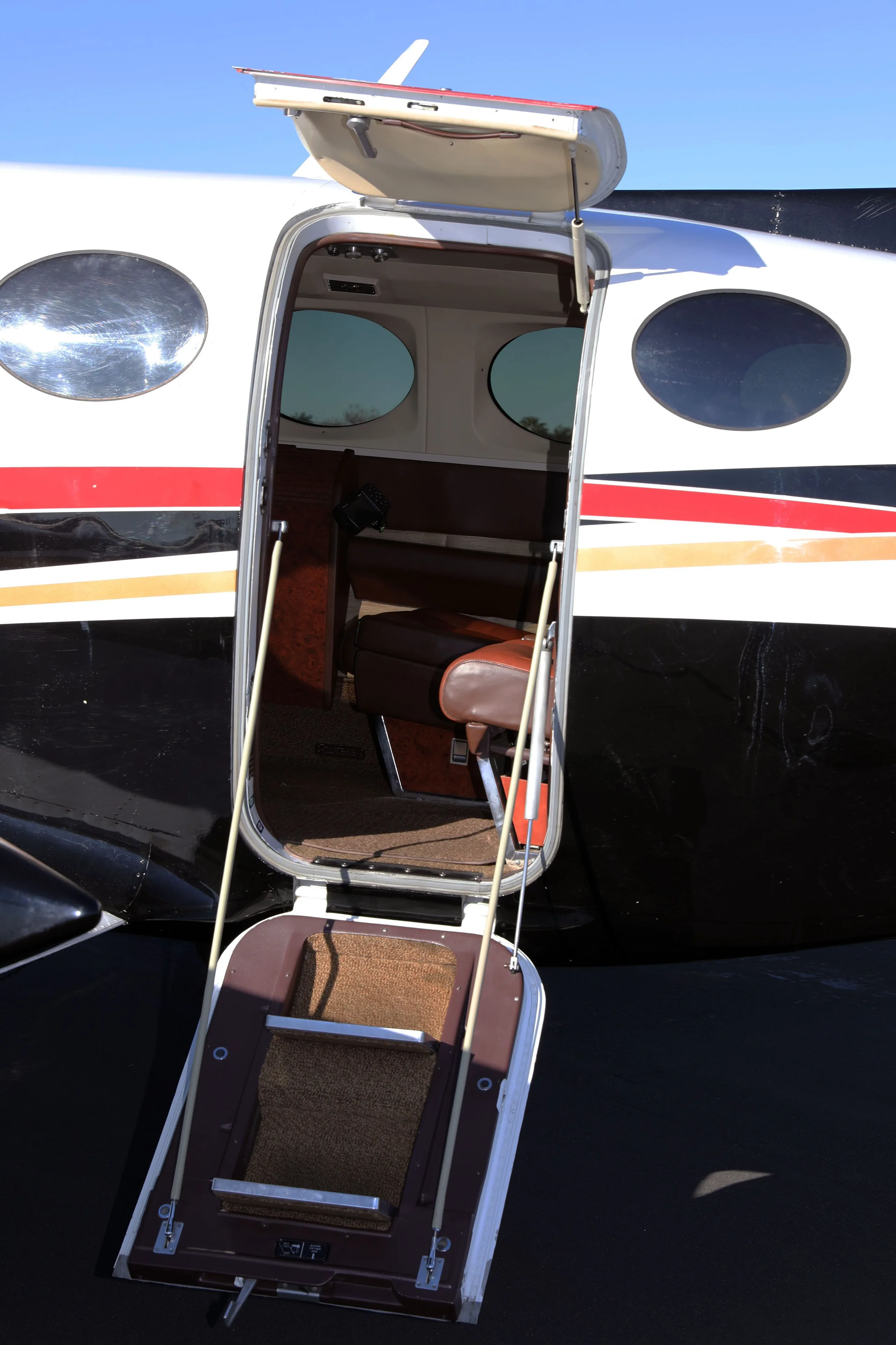 The open passenger door and retractable steps of the Cessna 414 Chancellor, showing a glimpse of the brown leather interior.