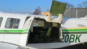 View of the interior of the Piper Lance II aircraft with green seats and open door.
