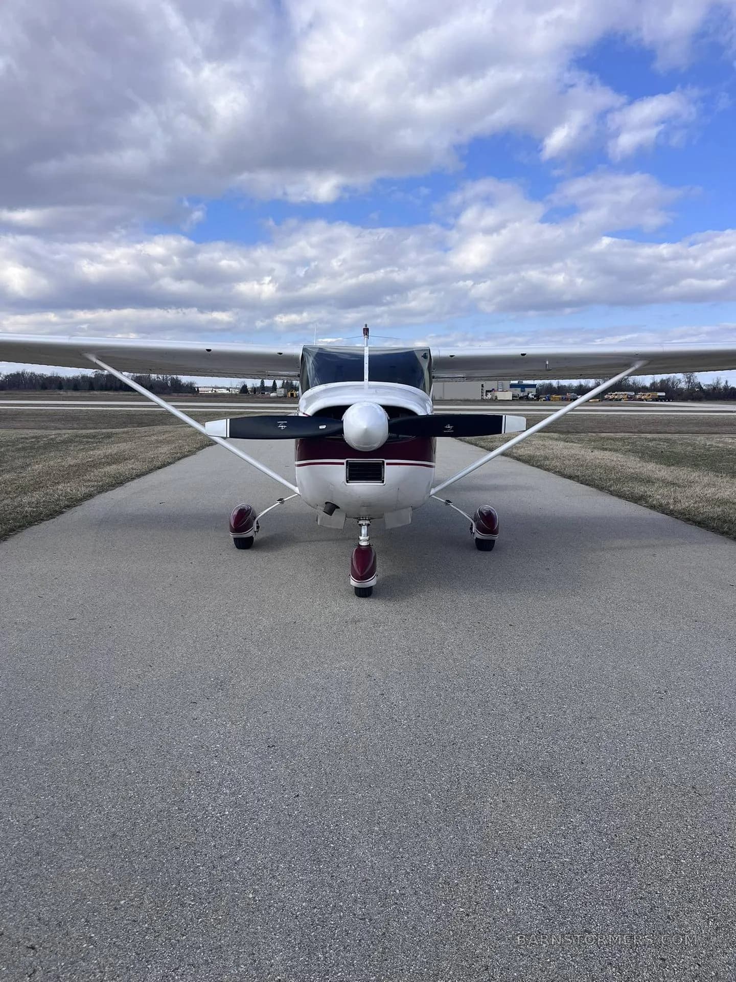 A maroon and white single-engine propeller aircraft (N3317U) viewed head-on, parked on an asphalt taxiway.