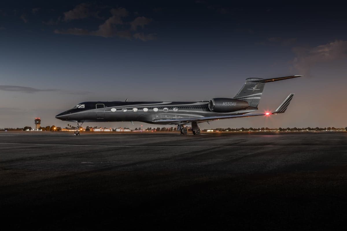 A Gulfstream G550 aircraft is parked on the tarmac at dusk.