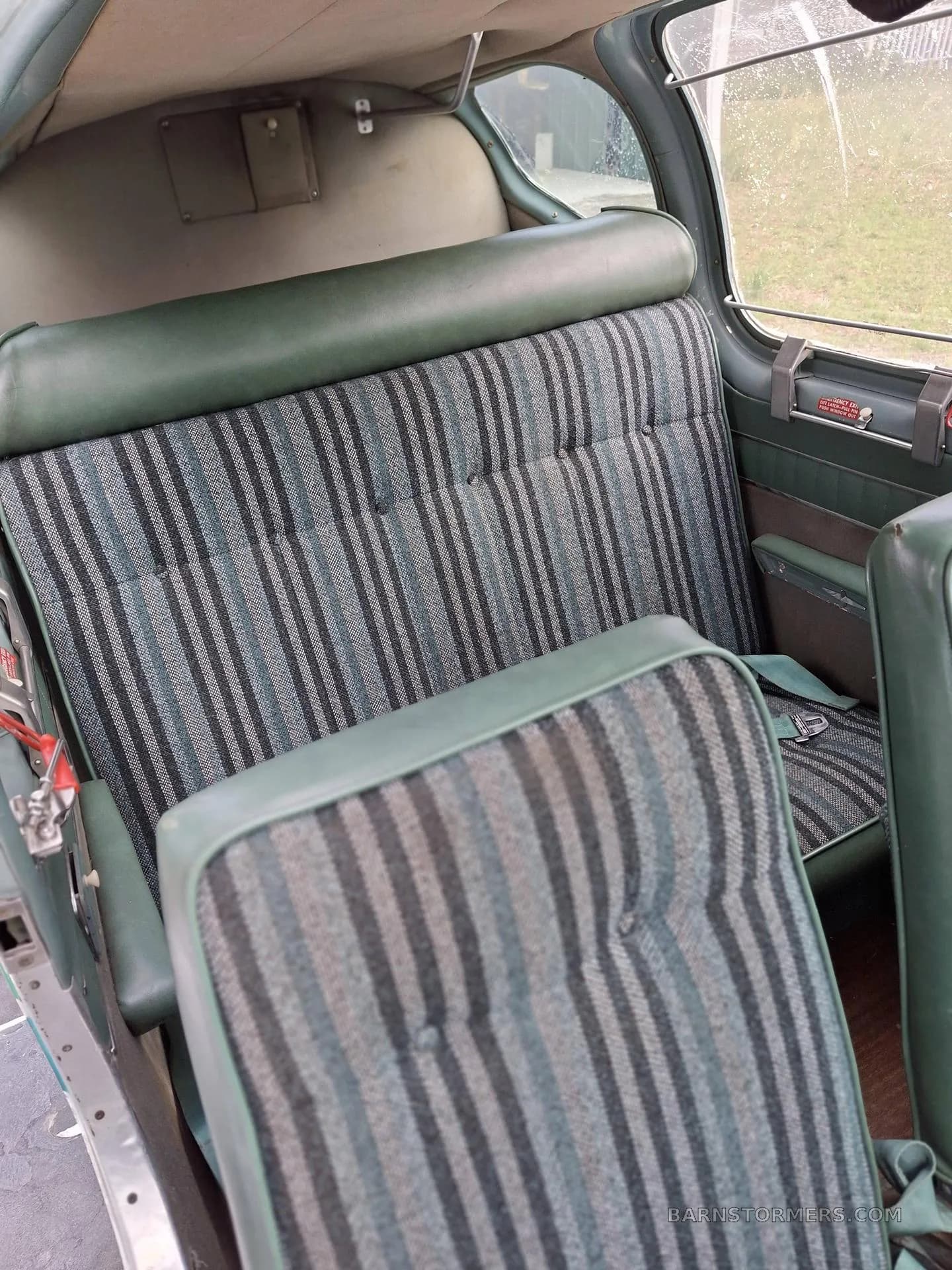 The rear passenger seats of an aircraft cabin, upholstered in green and striped fabric.