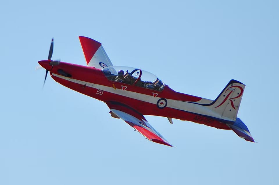 A23-050 aircraft in flight with red and white paint scheme.