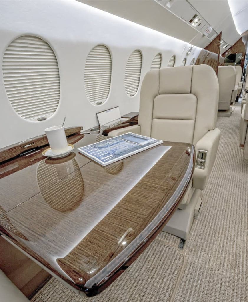 Close up of a leather seat and wood table in the interior cabin of a jet.