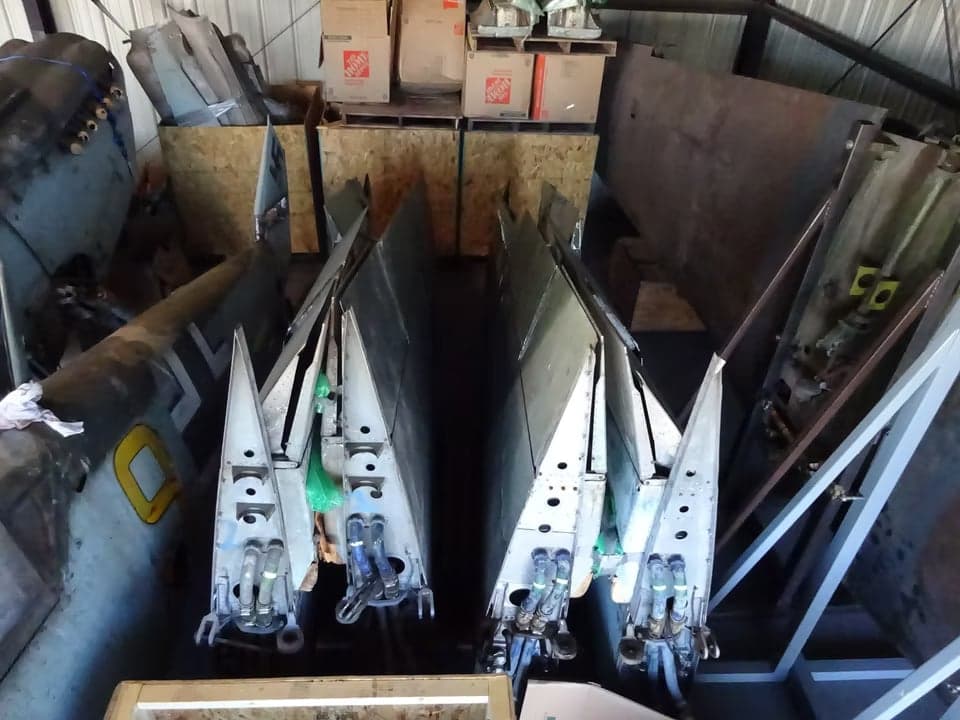 A disassembled Messerschmitt Bf 109 aircraft in a hangar, showing the tail and other parts.