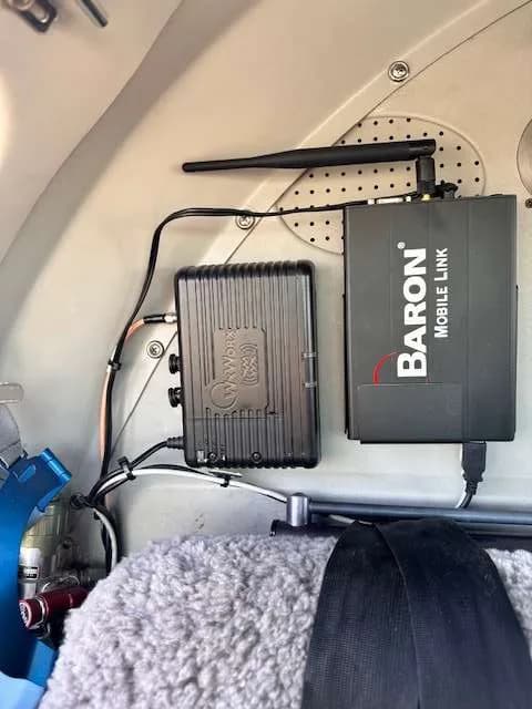 Two black electronic devices, labeled "BARON MOBILE LINK" and "W-WORK", mounted on an interior panel of the aircraft.