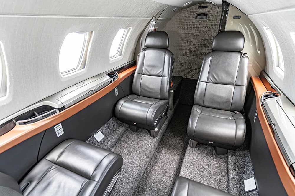 A side view of the aircraft cabin interior, featuring dark leather seats and large windows.
