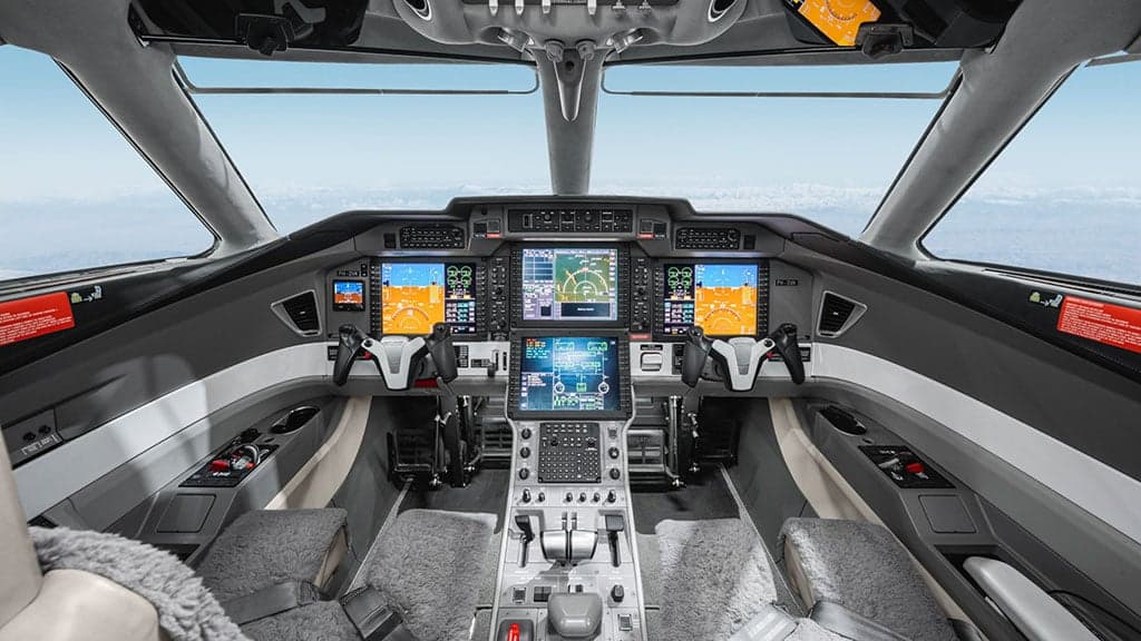 A detailed view of a modern aircraft cockpit with multiple large display screens.