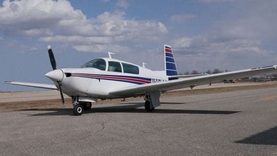 A white and blue single-engine aircraft is parked on the tarmac.