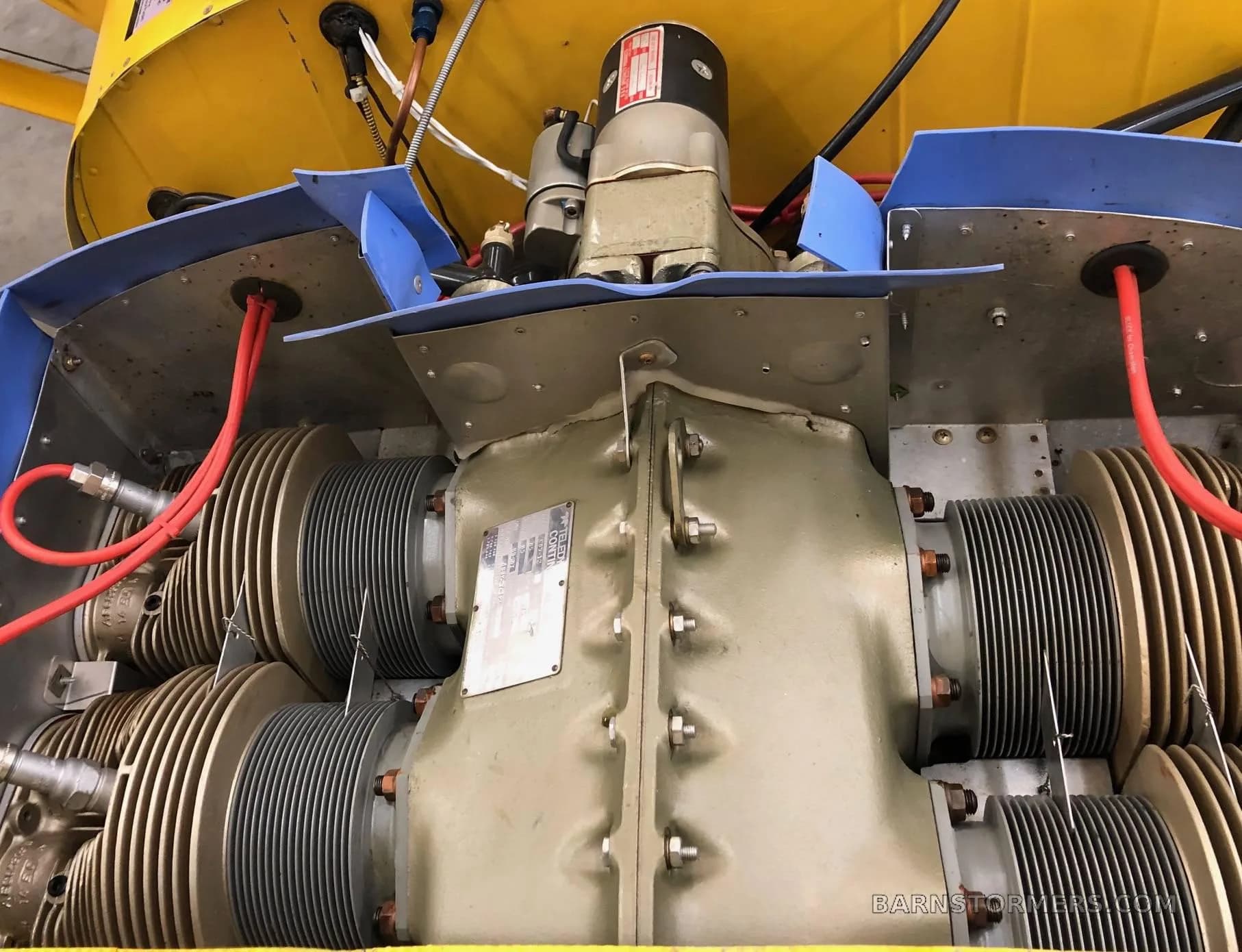 A close-up view of the aircraft's engine, showing cylinders and red ignition wires.
