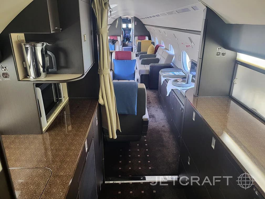 A view from the galley looking into the business jet cabin, showing a microwave and coffee maker.