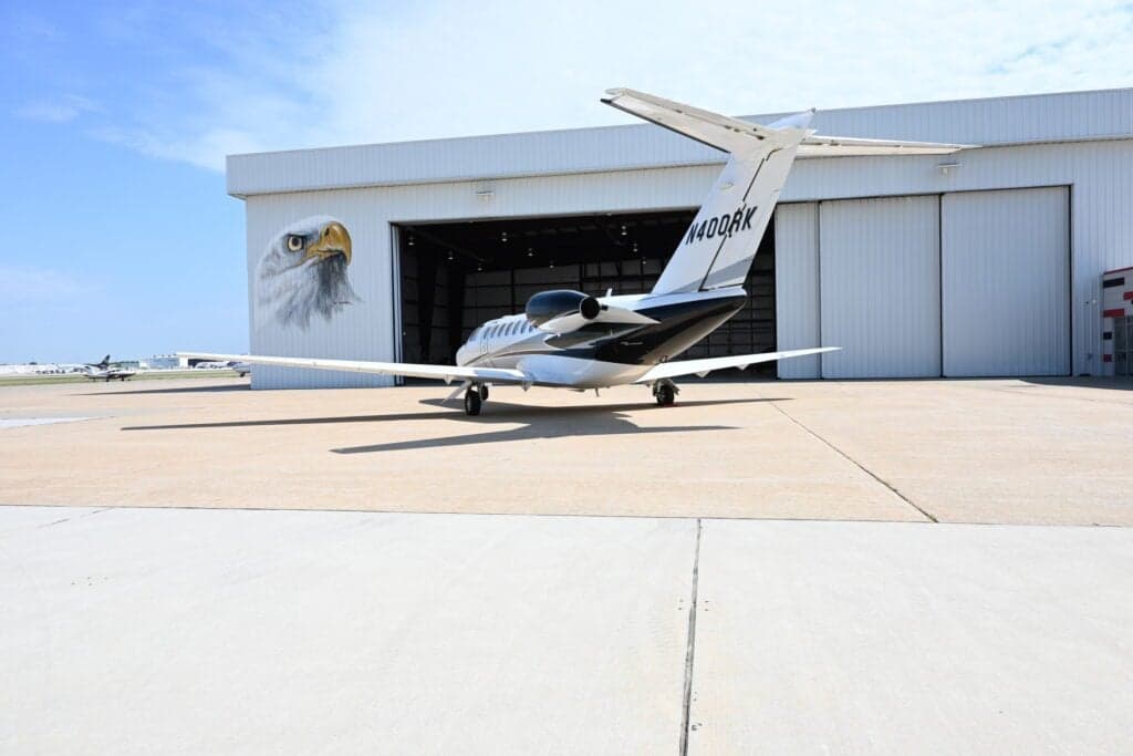Rear view of N400RK Cessna Citation CJ3+ parked in front of a hangar with an eagle mural.
