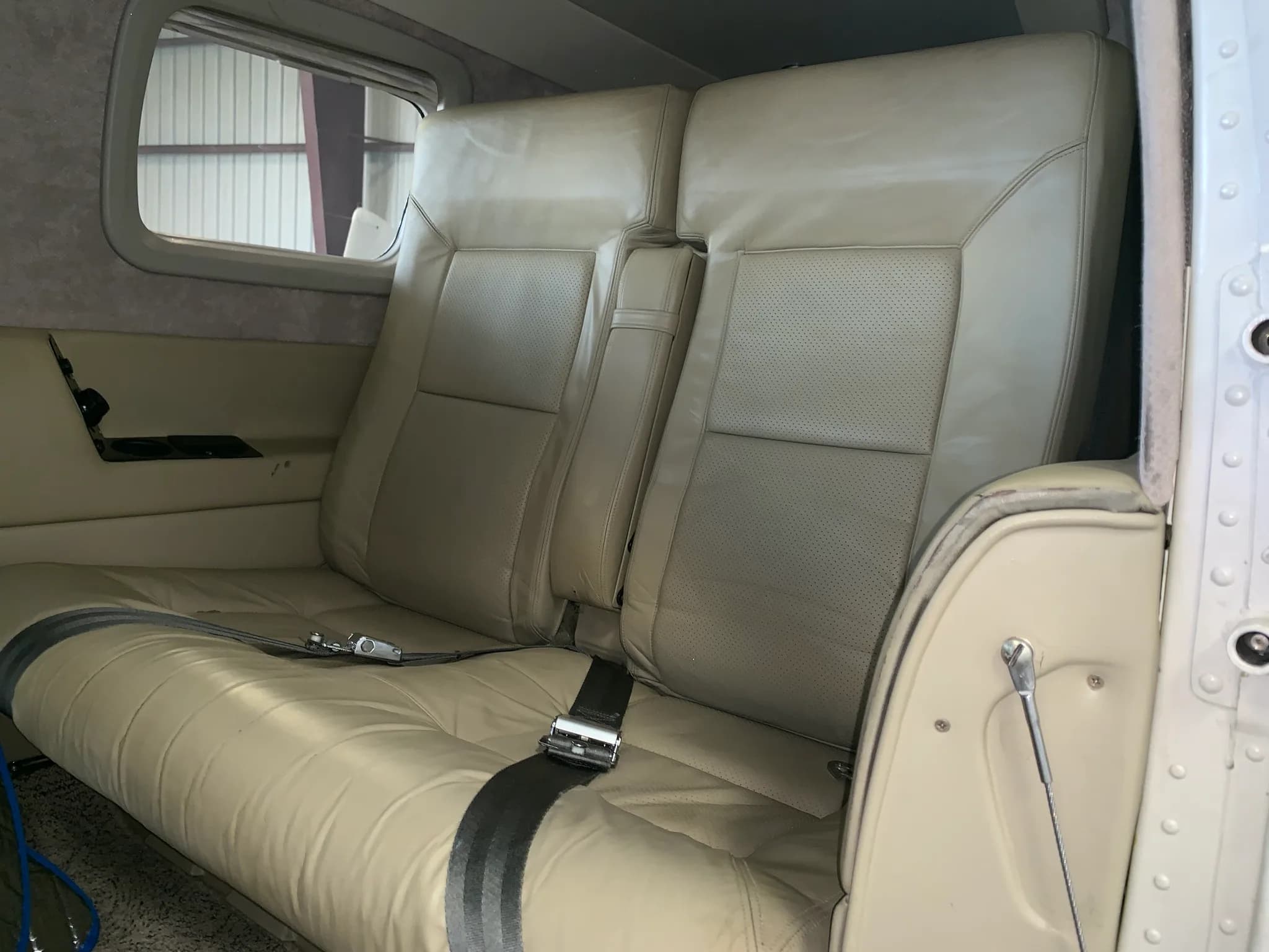 A side view of the beige leather passenger seats in the cabin interior of the Piper Mirage aircraft.