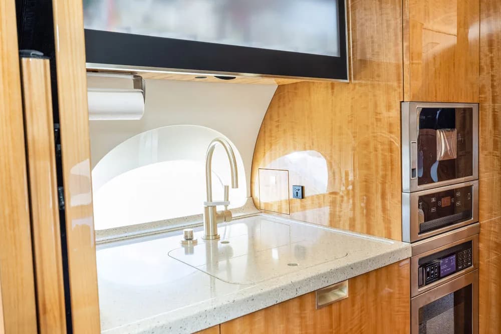 A view of the aircraft's galley counter with light wood cabinetry and a window in the background.