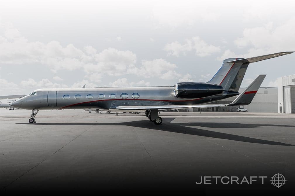 Side view of a silver and black Gulfstream G650 on the tarmac.