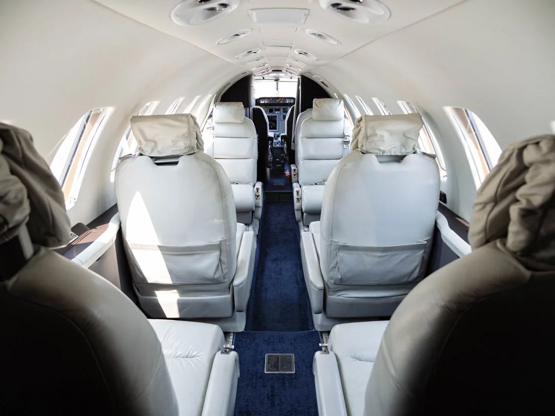 View down the aisle of the aircraft cabin with white leather seats.