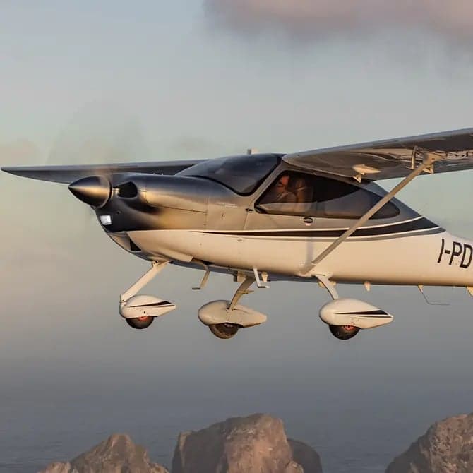 Tecnam P2006T in flight over the ocean.