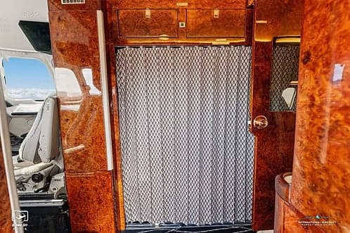 A view of the interior of a jet aircraft, showing a curtained doorway.