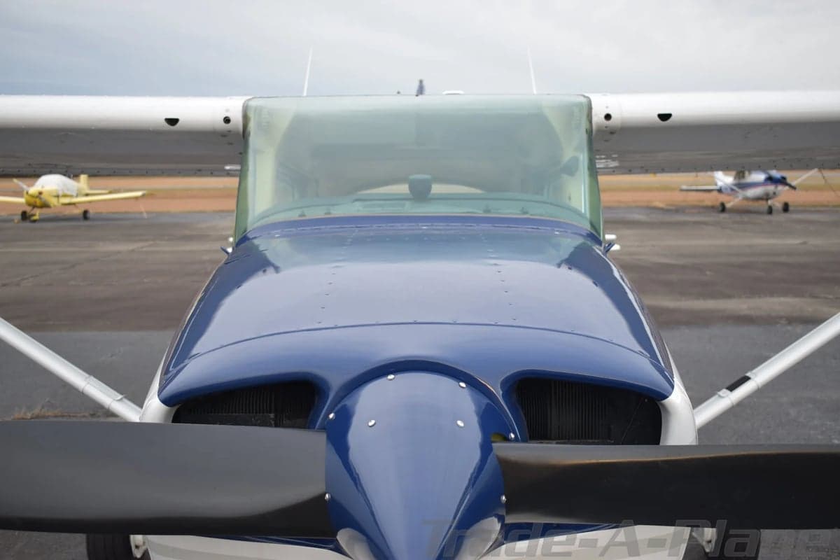 A close-up top-down view of the blue nose and windshield of a Cessna 172 aircraft.