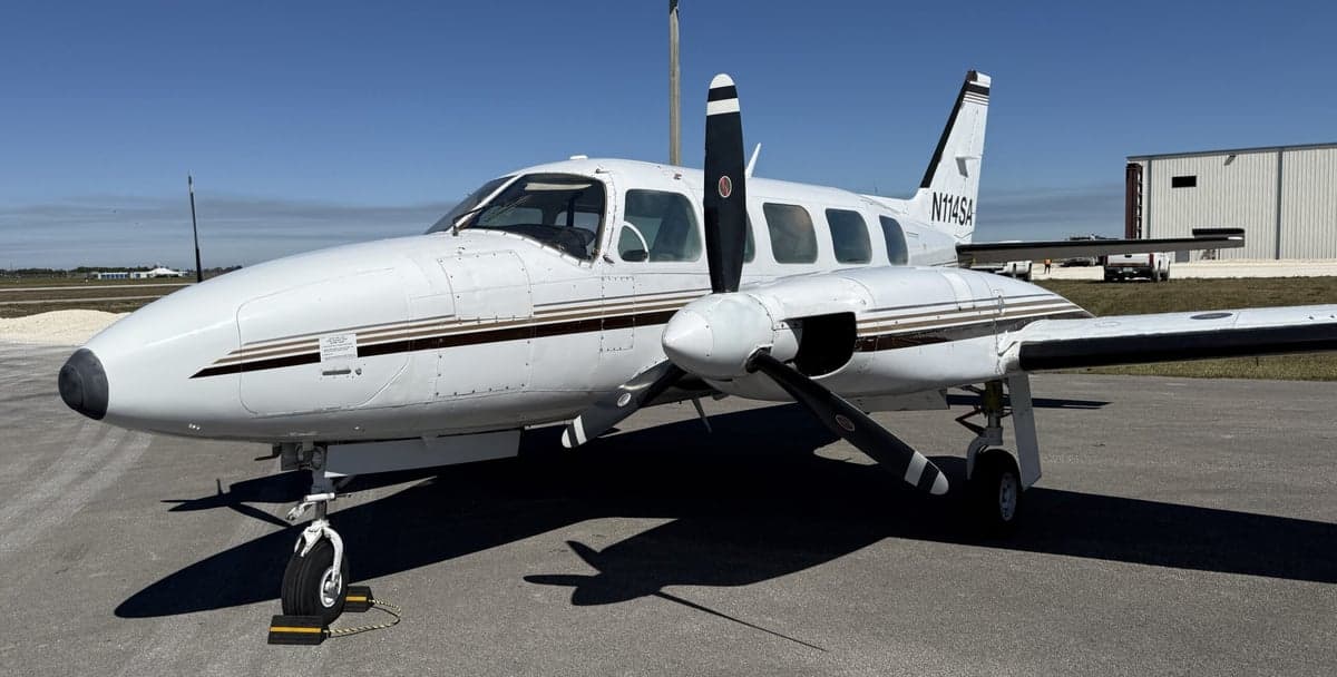 Side view of the twin-engine aircraft N114SA on the tarmac.