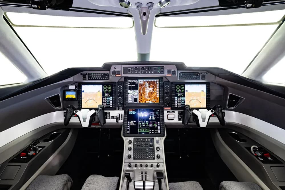 View of the aircraft's interior cabin with white leather seats and tables.
