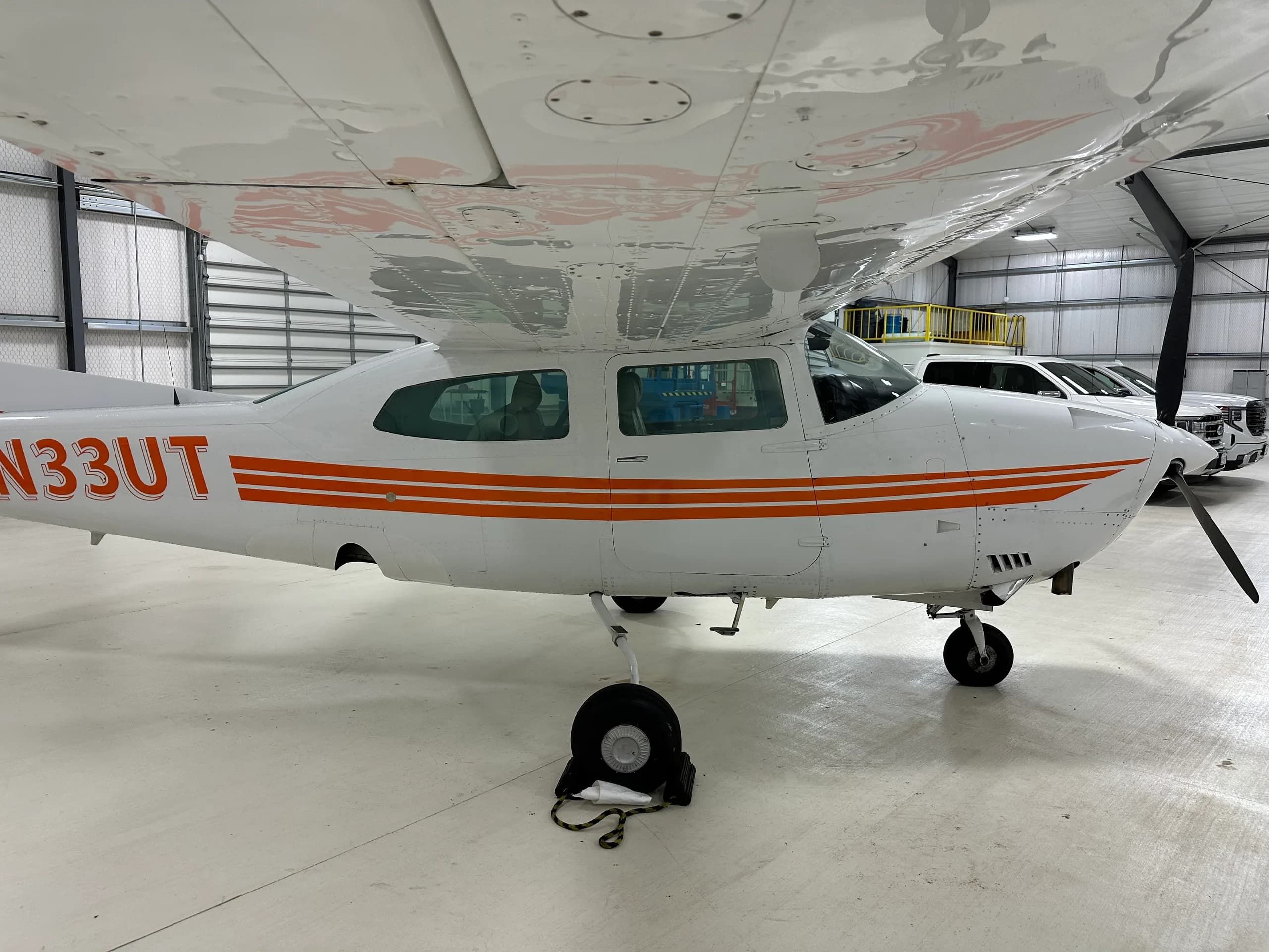 A Cessna 206 Stationair aircraft with orange stripes parked in a hangar.