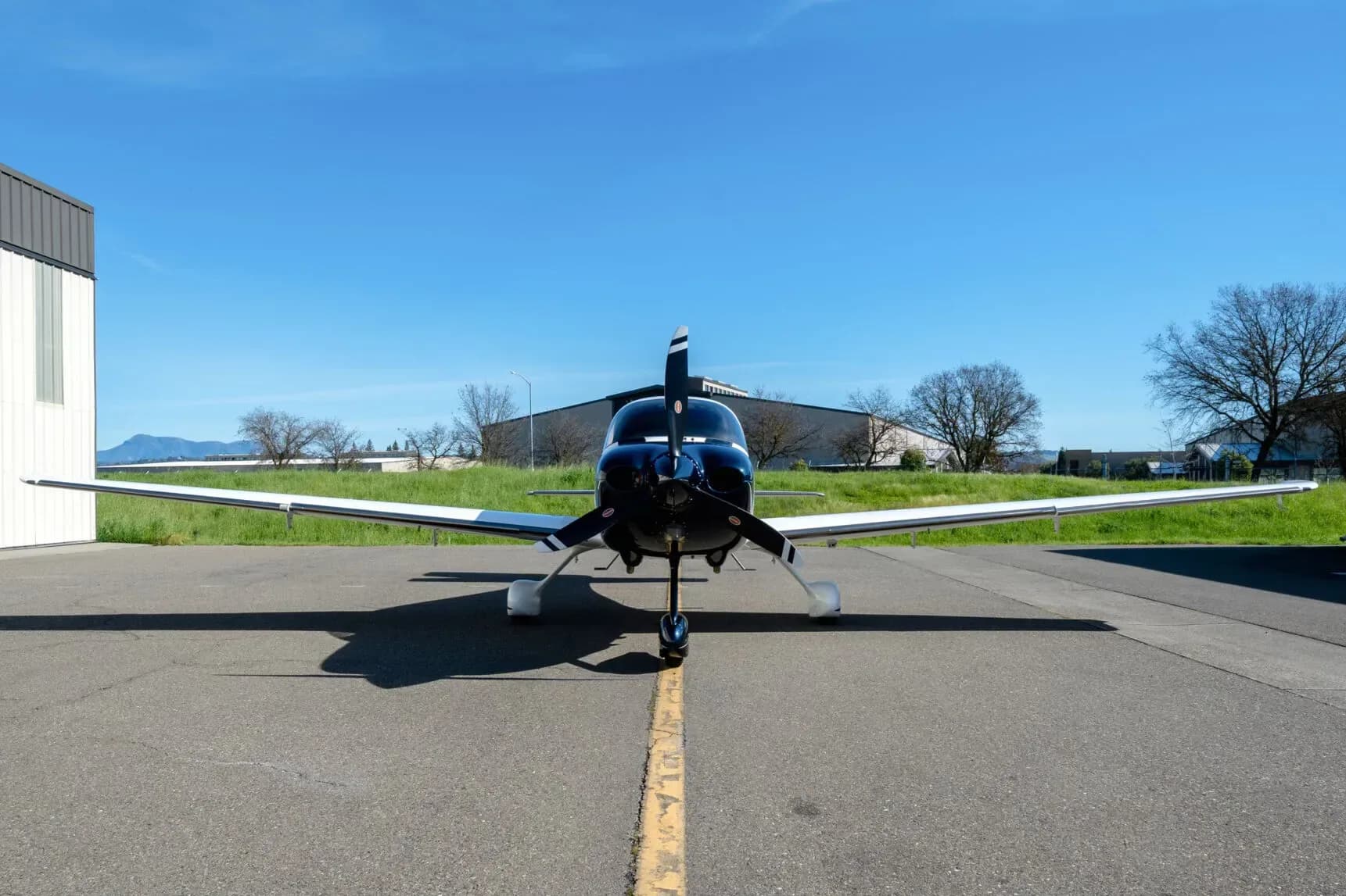 A head-on view of a white and dark blue Cirrus SR22 aircraft, registration N157AT, parked on an asphalt apron.