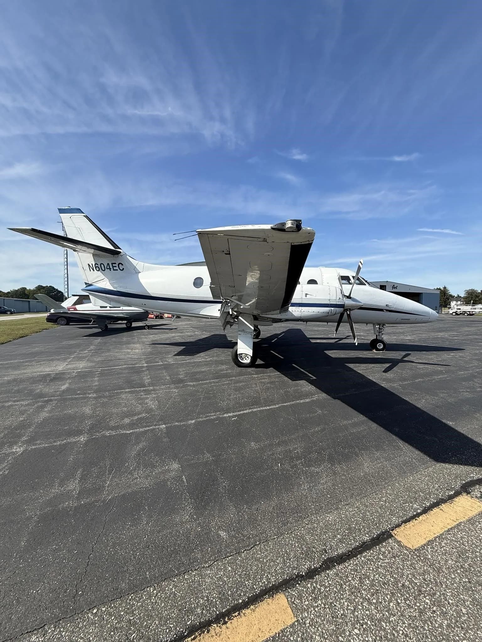 A low-angle front-quarter view of a white Jetstream 31 aircraft with blue accents, tail number N604EC, parked on an asphalt tarmac.